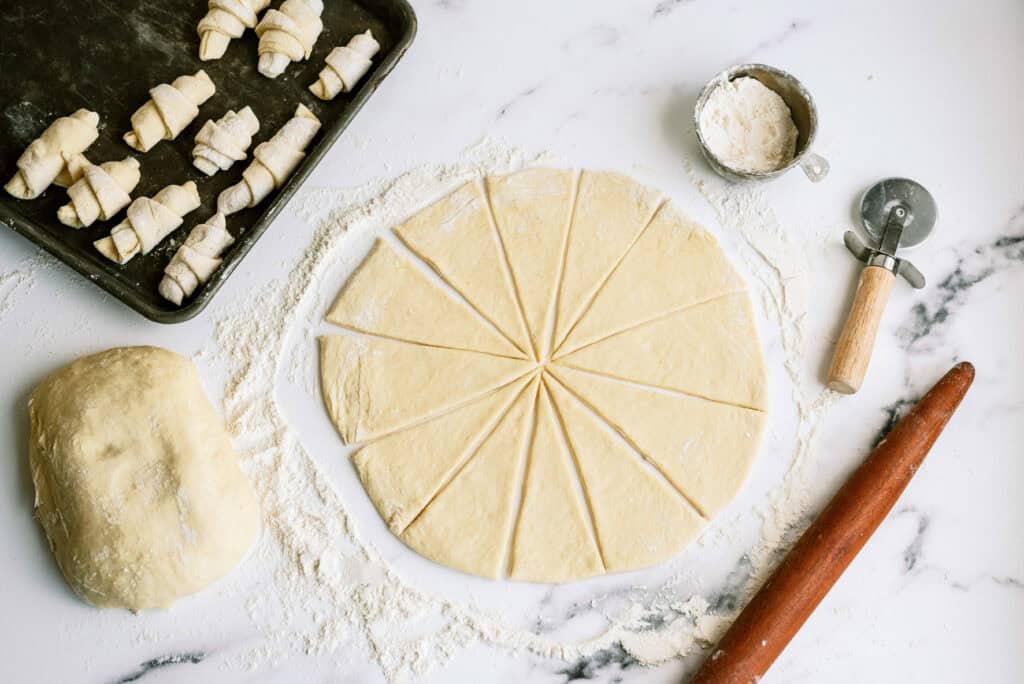 Dough circle cut into pizza slices on counter top.