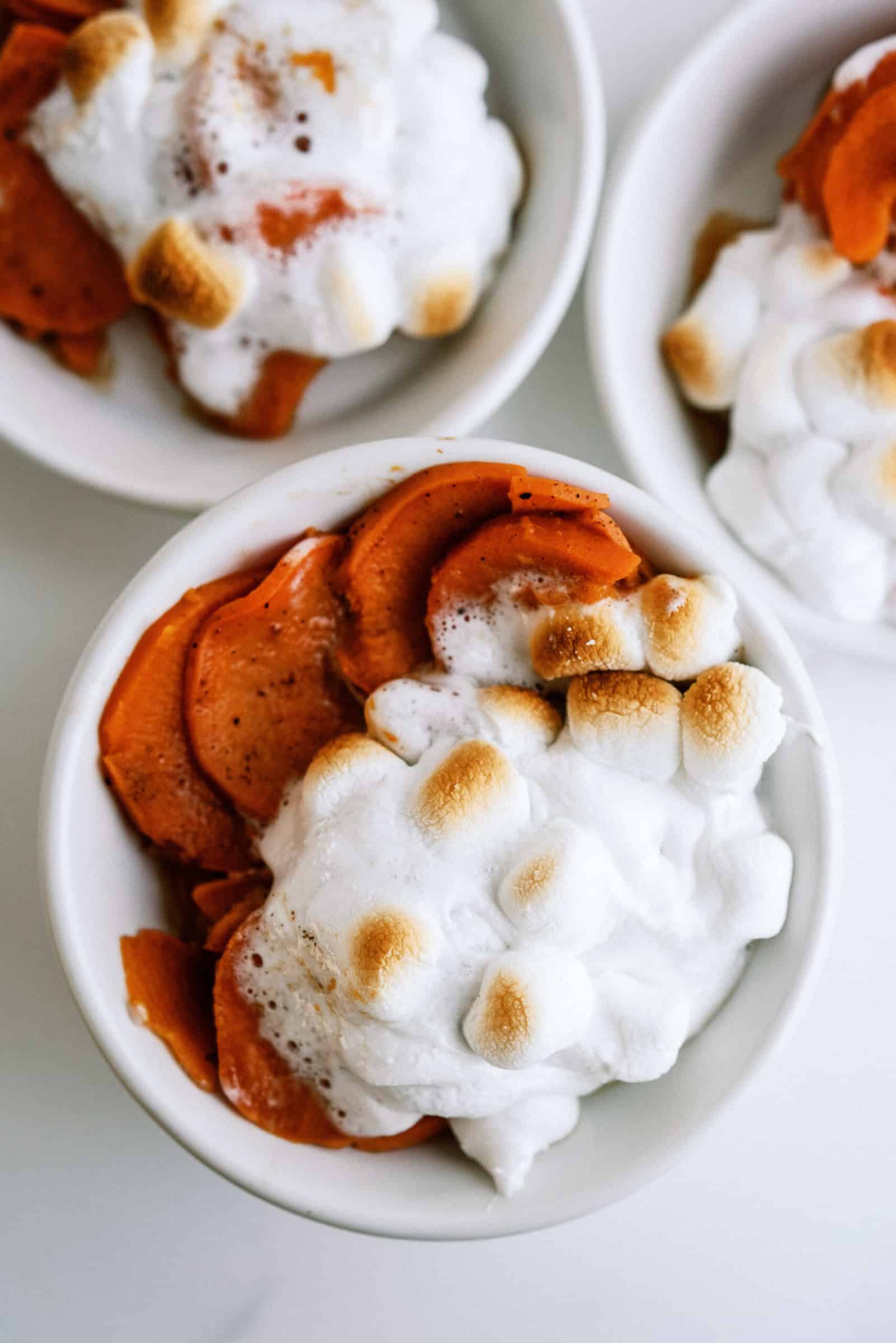 sweet potatoes topped with golden marshmallows in 3 white bowls