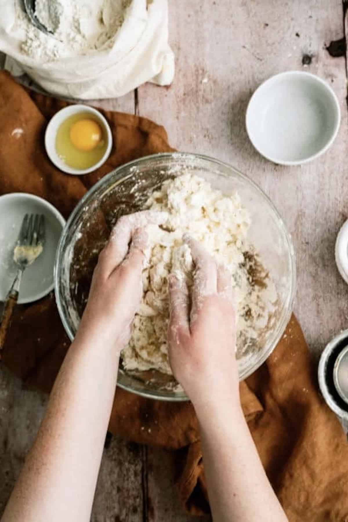 Mixing together ingredients in glass mixing bowl by hand to make a pie crust.