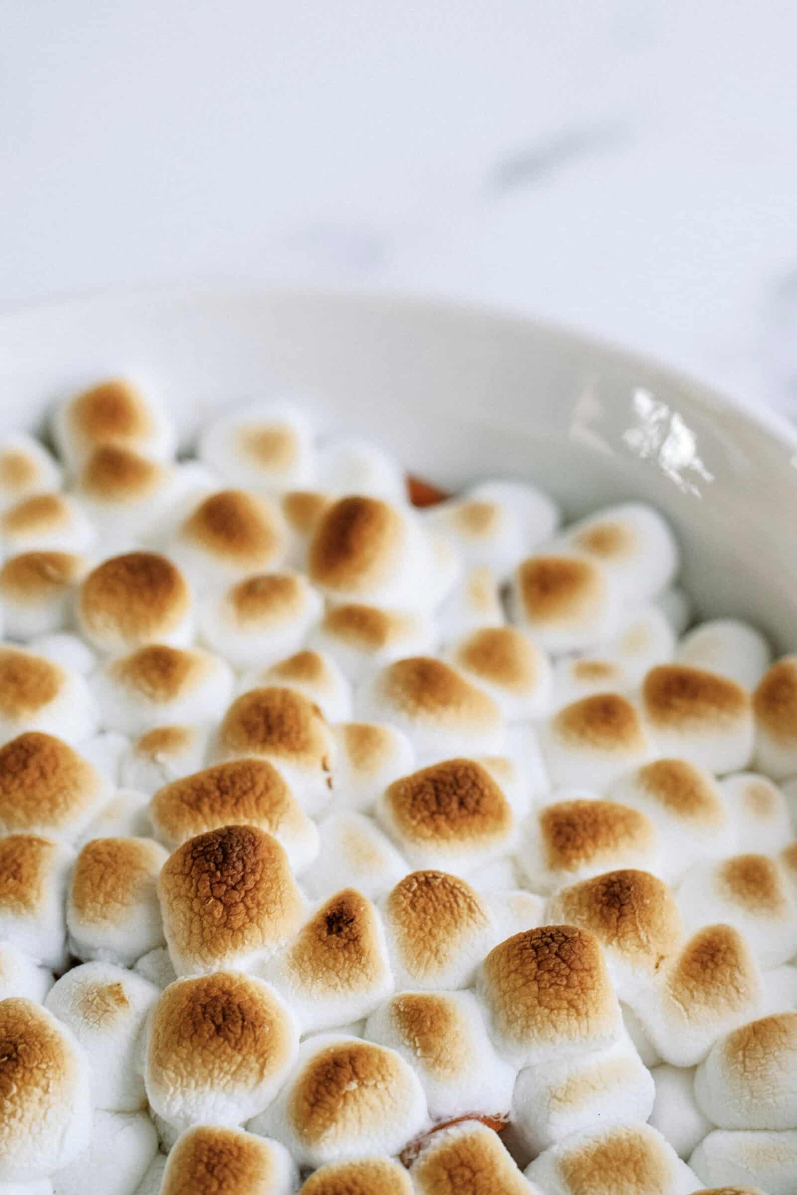 sweet potatoes covered in browned marshmallows in a white dish 