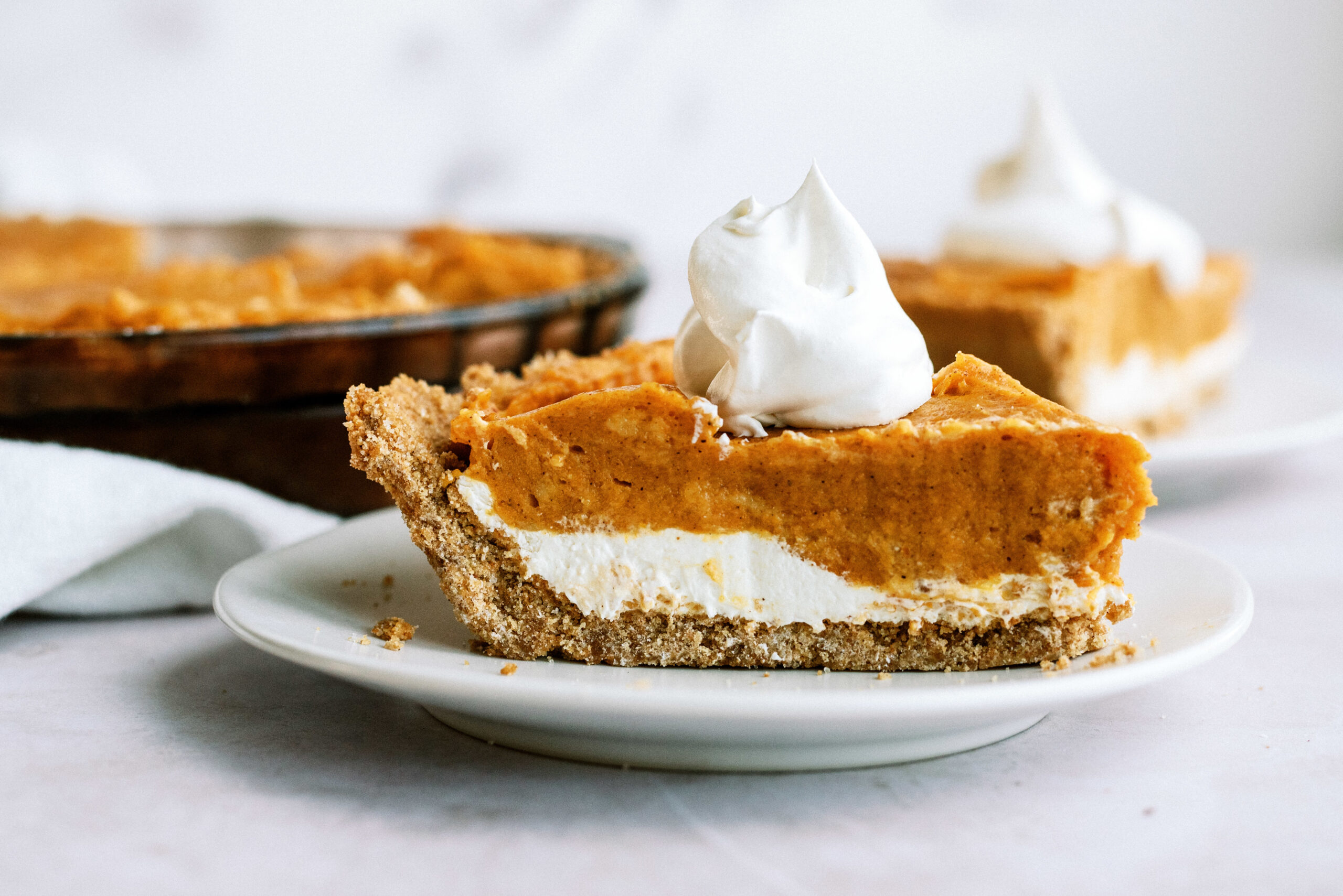 One slice of Easy Double Layer Pumpkin Pie on a plate topped with whip cream