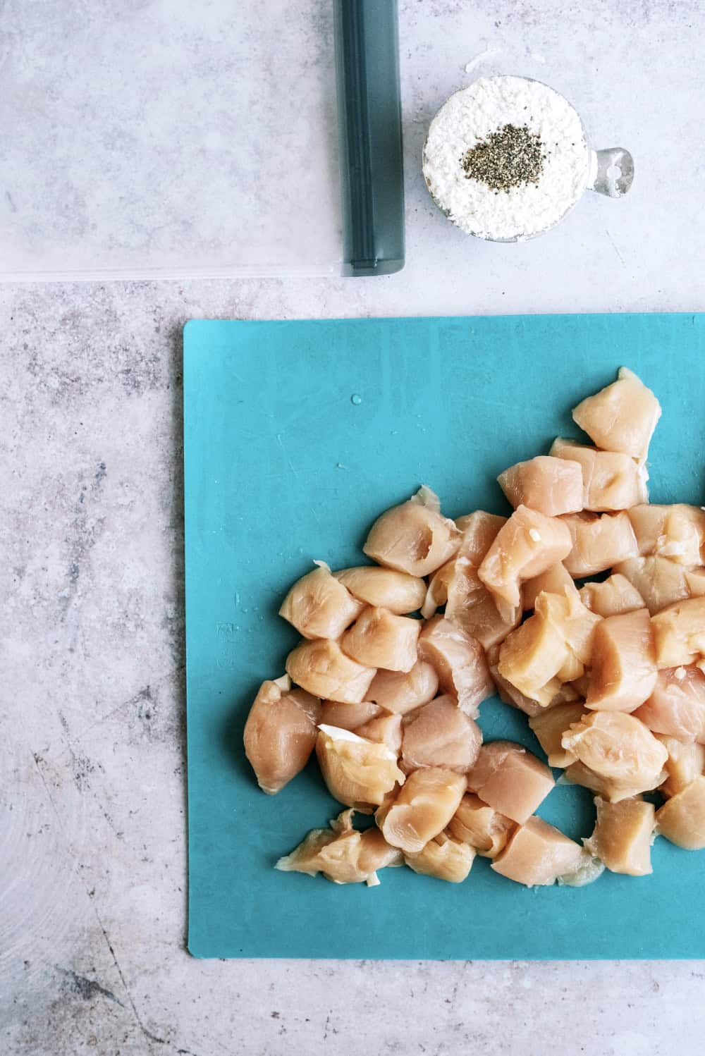 raw chicken in bite-size pieces on a cutting board