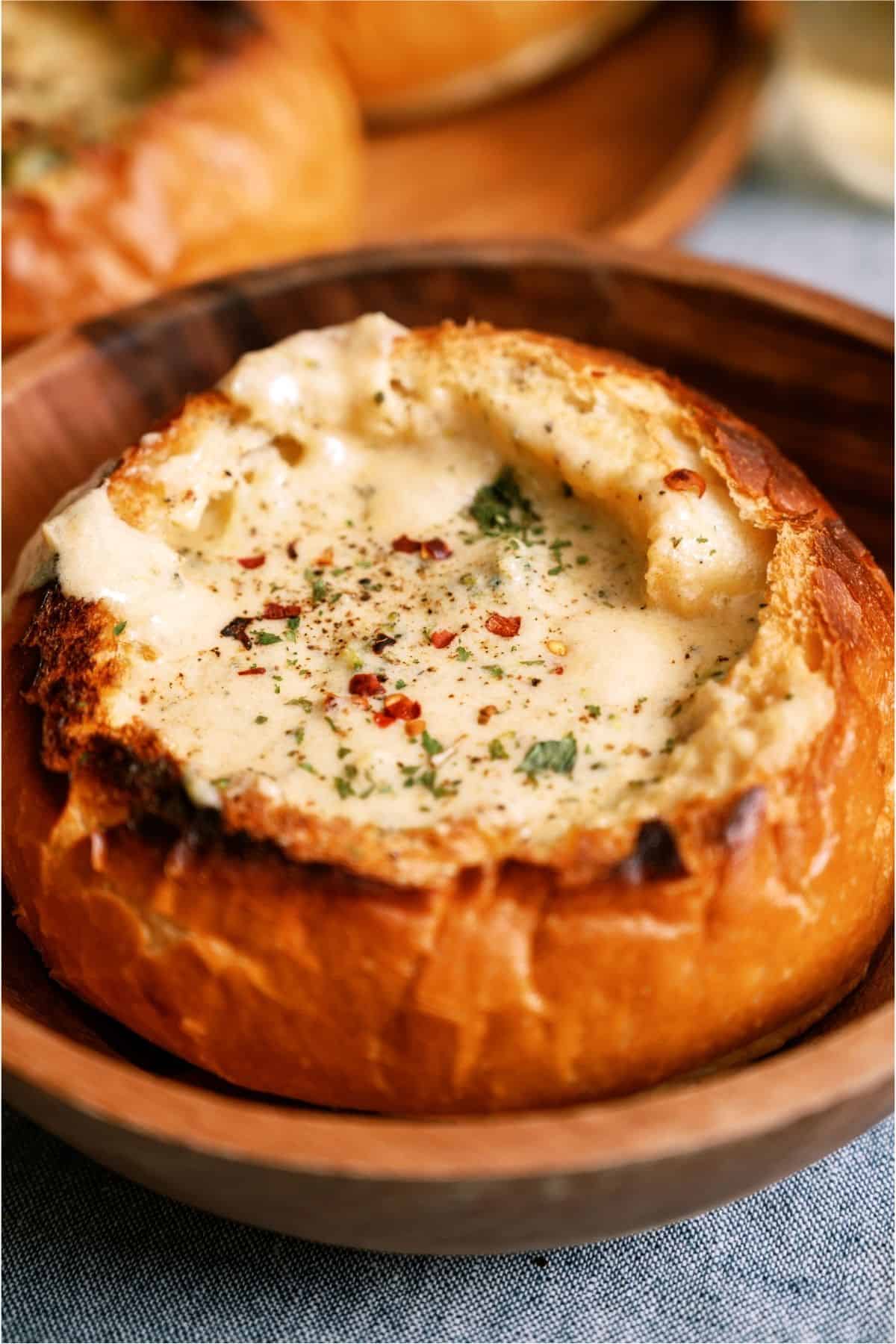 A bread bowl with a serving of Slow Cooker Broccoli Cheddar Soup in it.