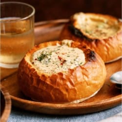 A bread bowl filled with Slow Cooker Broccoli Cheddar Soup on a plate.