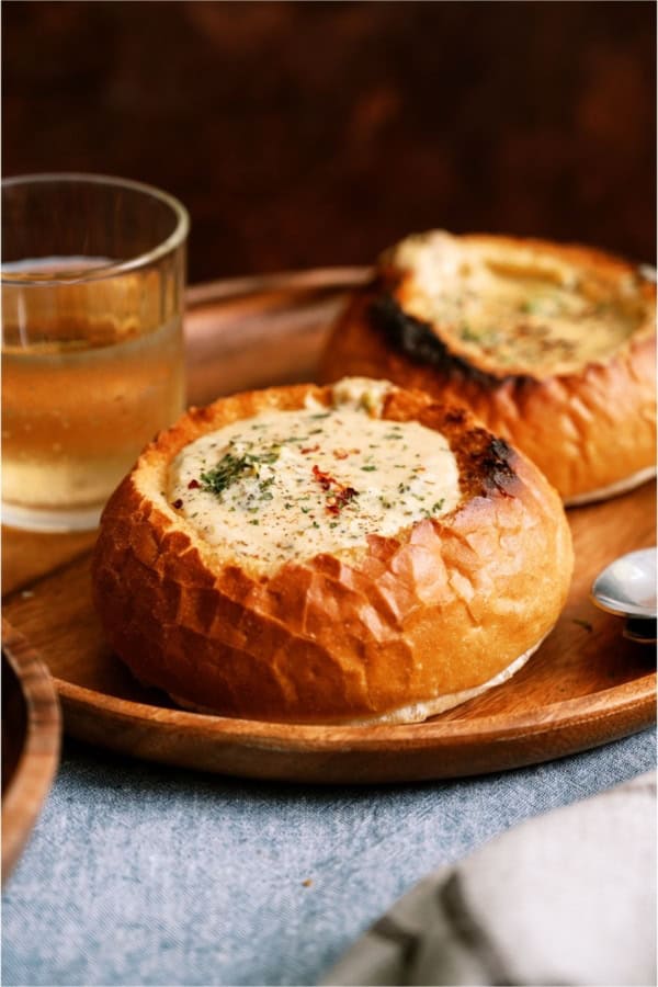 A bread bowl filled with Slow Cooker Broccoli Cheddar Soup on a plate.