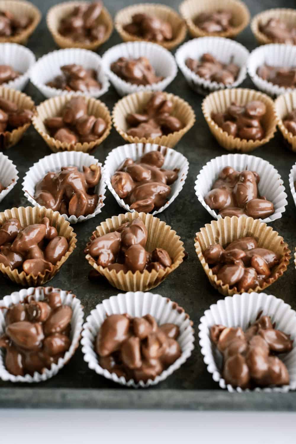 chocolate clusters in liners all lined up on a cookie sheet