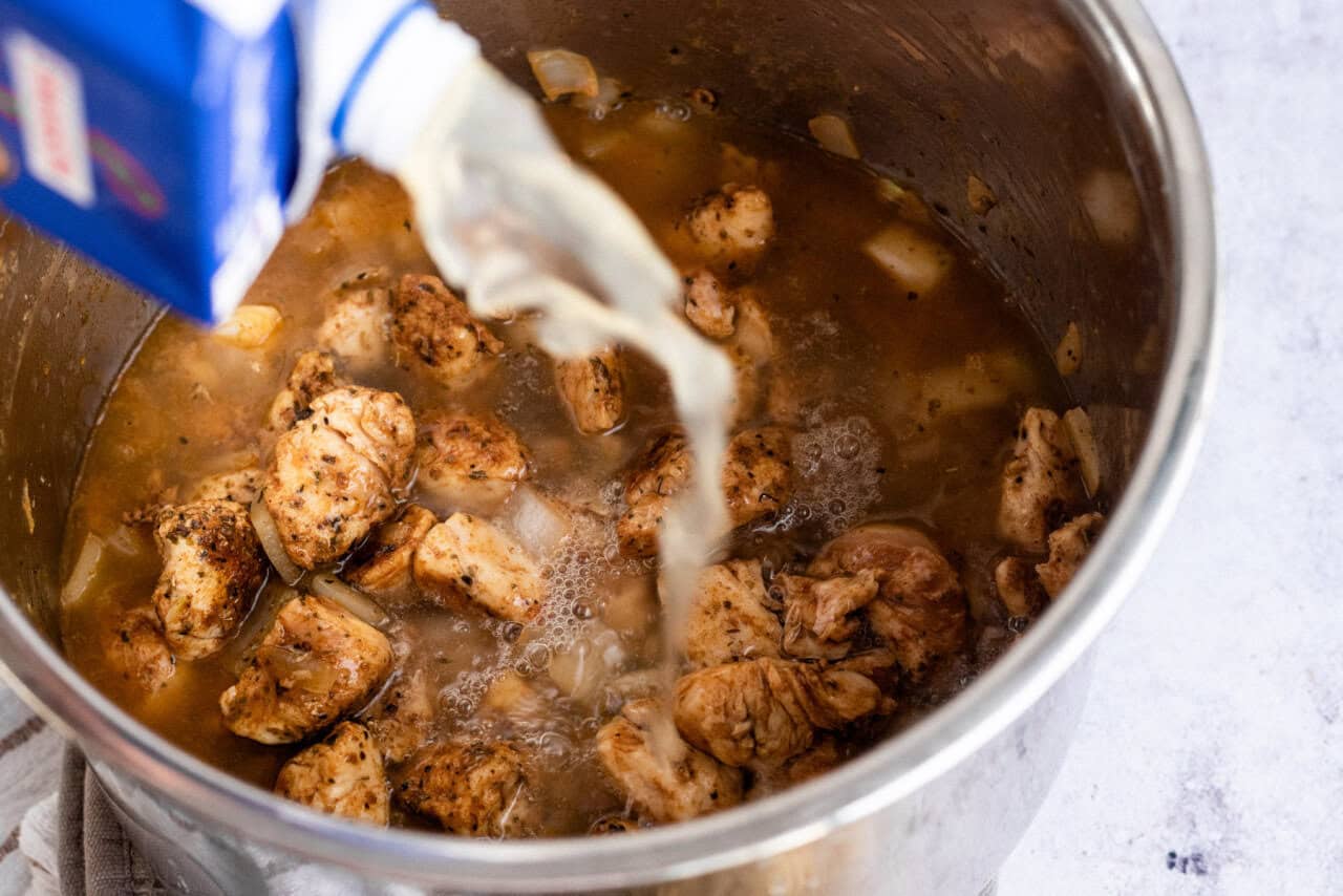 chicken broth added to the Instant Pot with chicken and onions