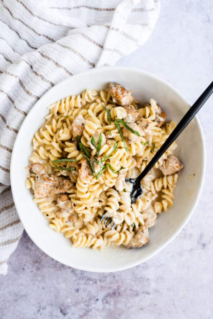 Top view of a serving of Instant Pot Cheesy Chicken and Pasta in a bowl with a fork.
