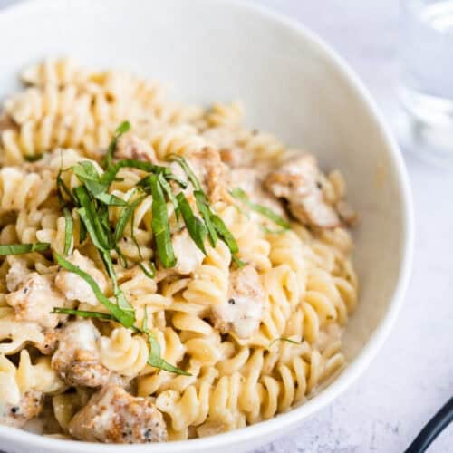 A serving of Instant Pot Cheesy Chicken and Pasta in a white bowl.