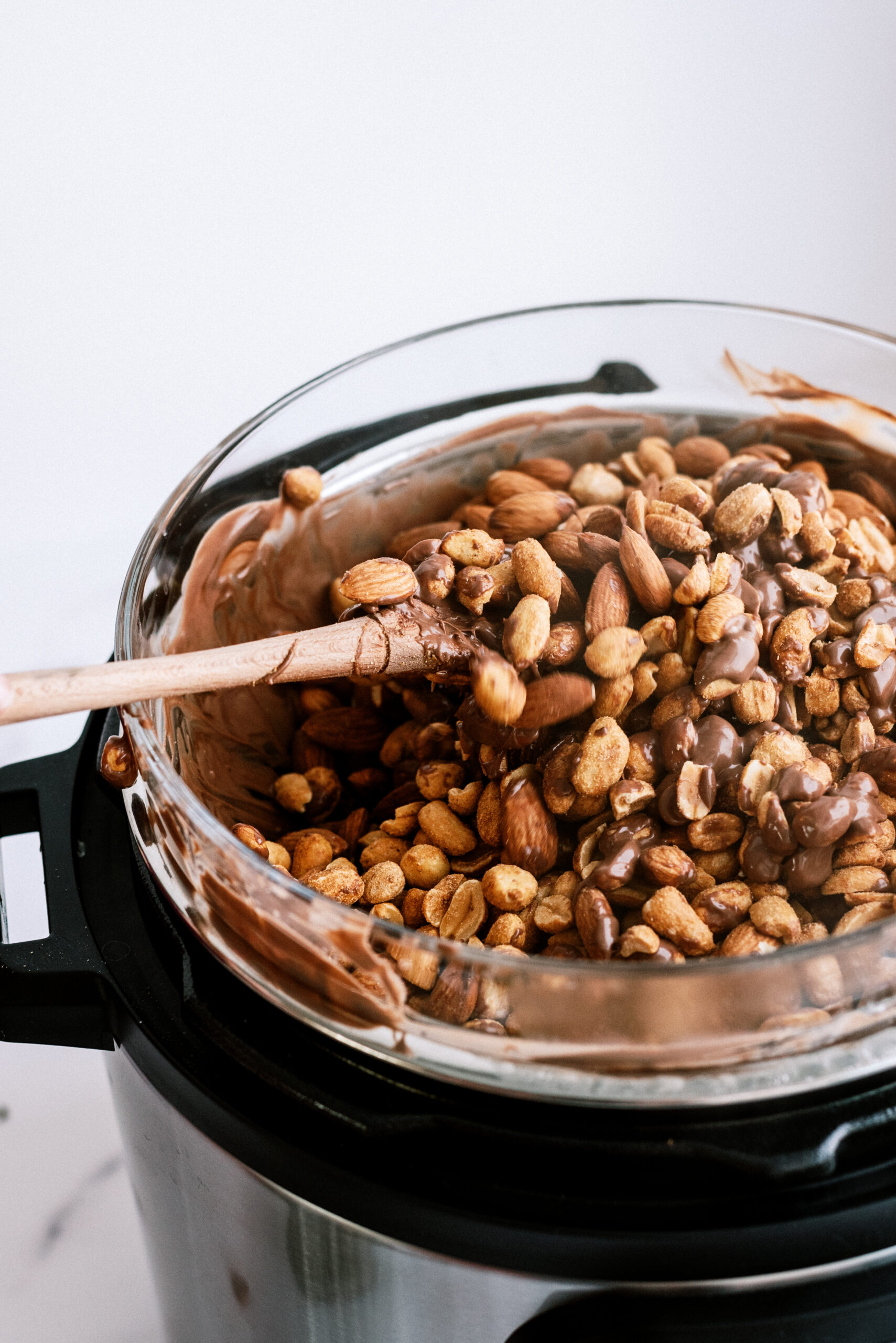 peanuts mixed in with melted chocolate in bowl on top of pressure cooker