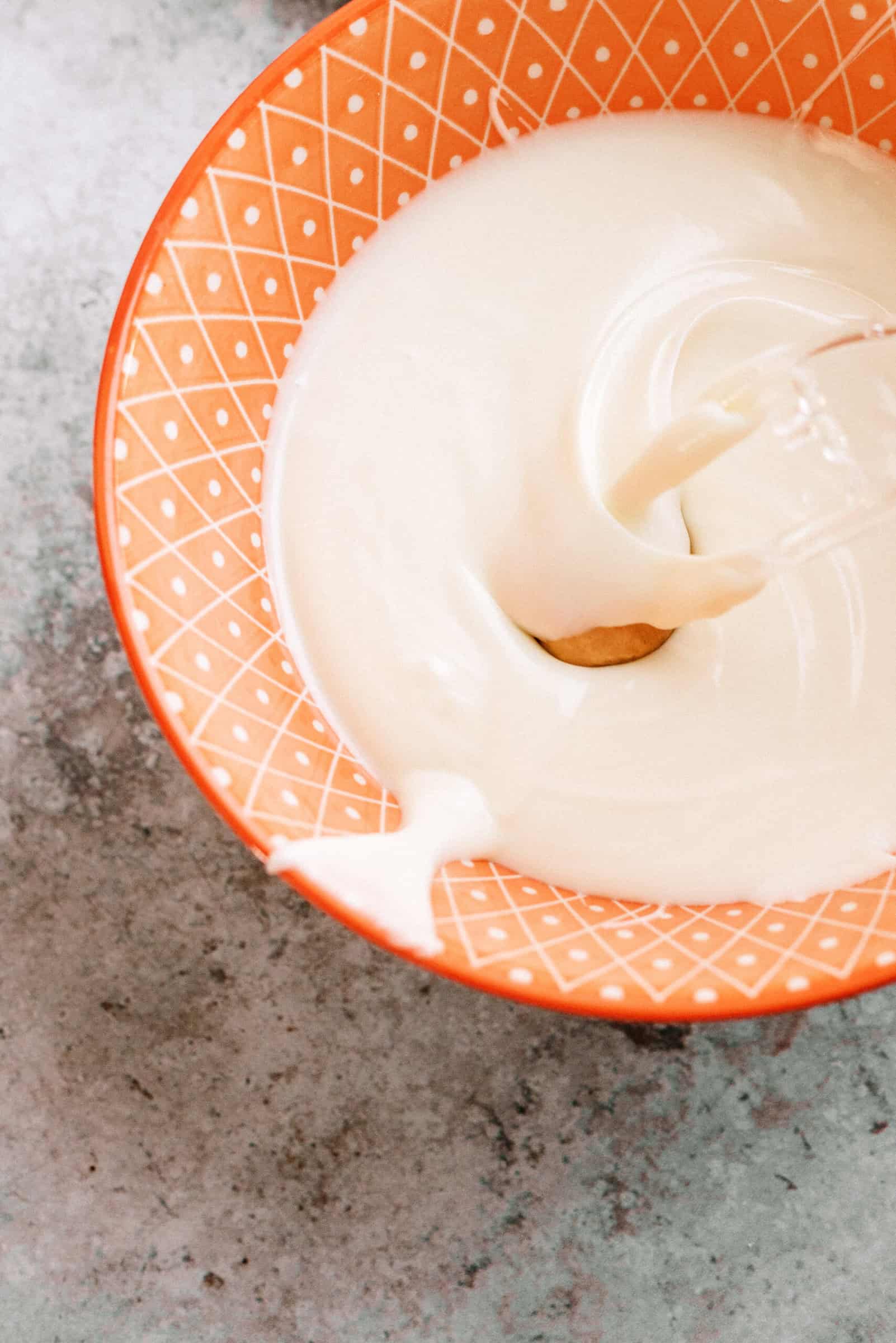 melted white chocolate with peanut butter ball being dipped in the middle of the bowl