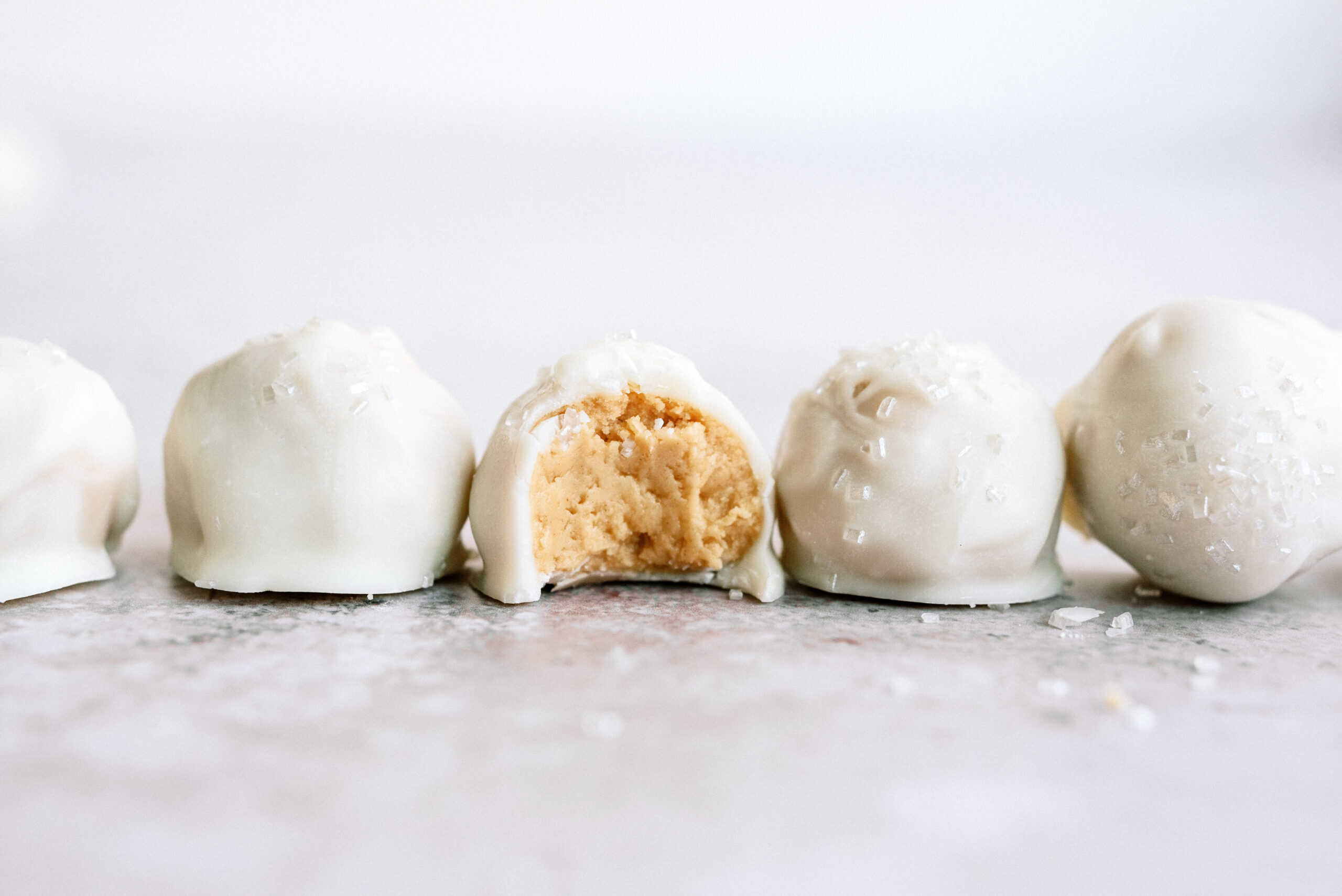 peanut butter snowballs in a line with a bite out of the middle one