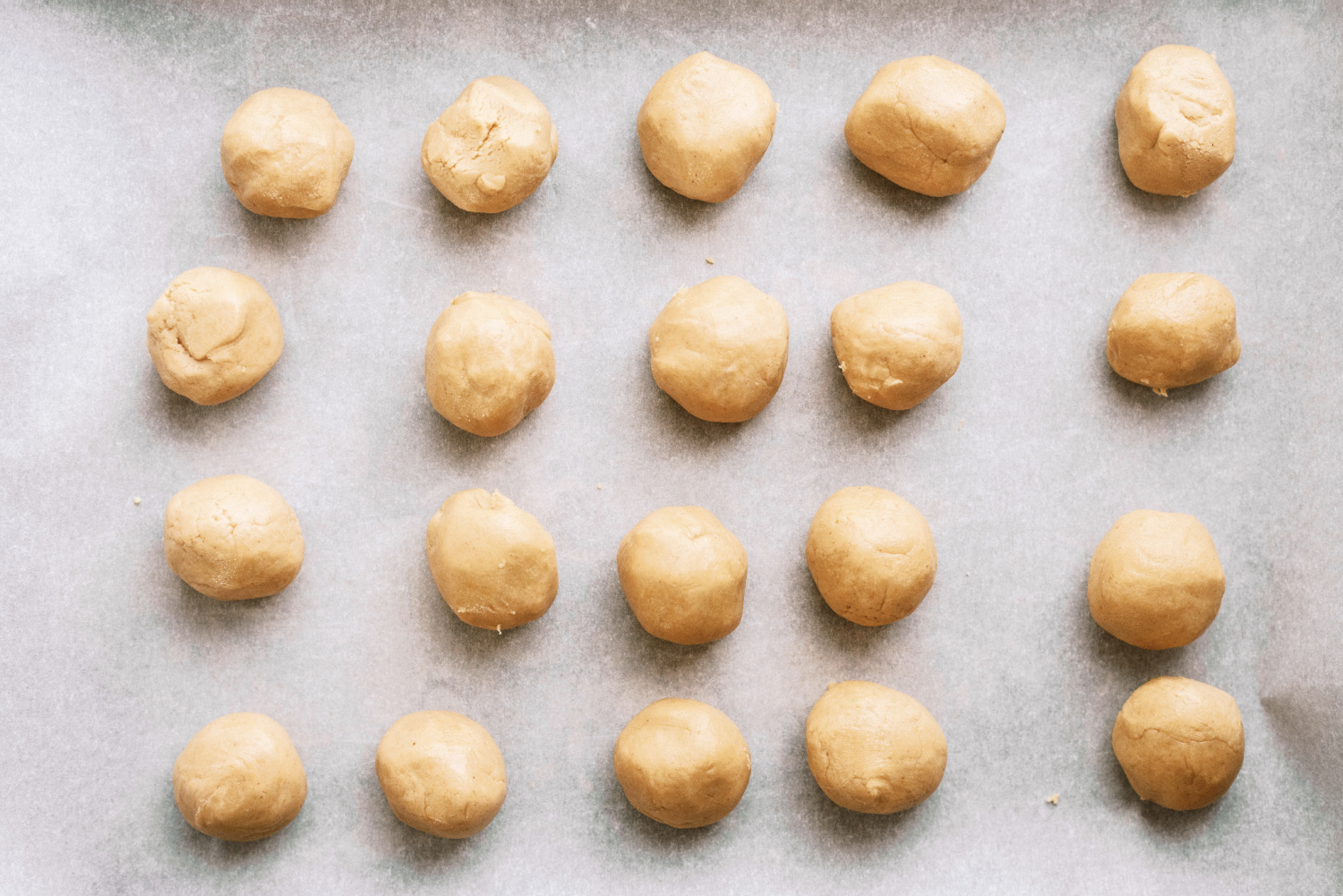 peanut butter dough balls spread out on a cookie sheet