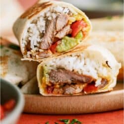 Close up of a Crispy Steak Burrito cut in half to show the ingredients on the inside.