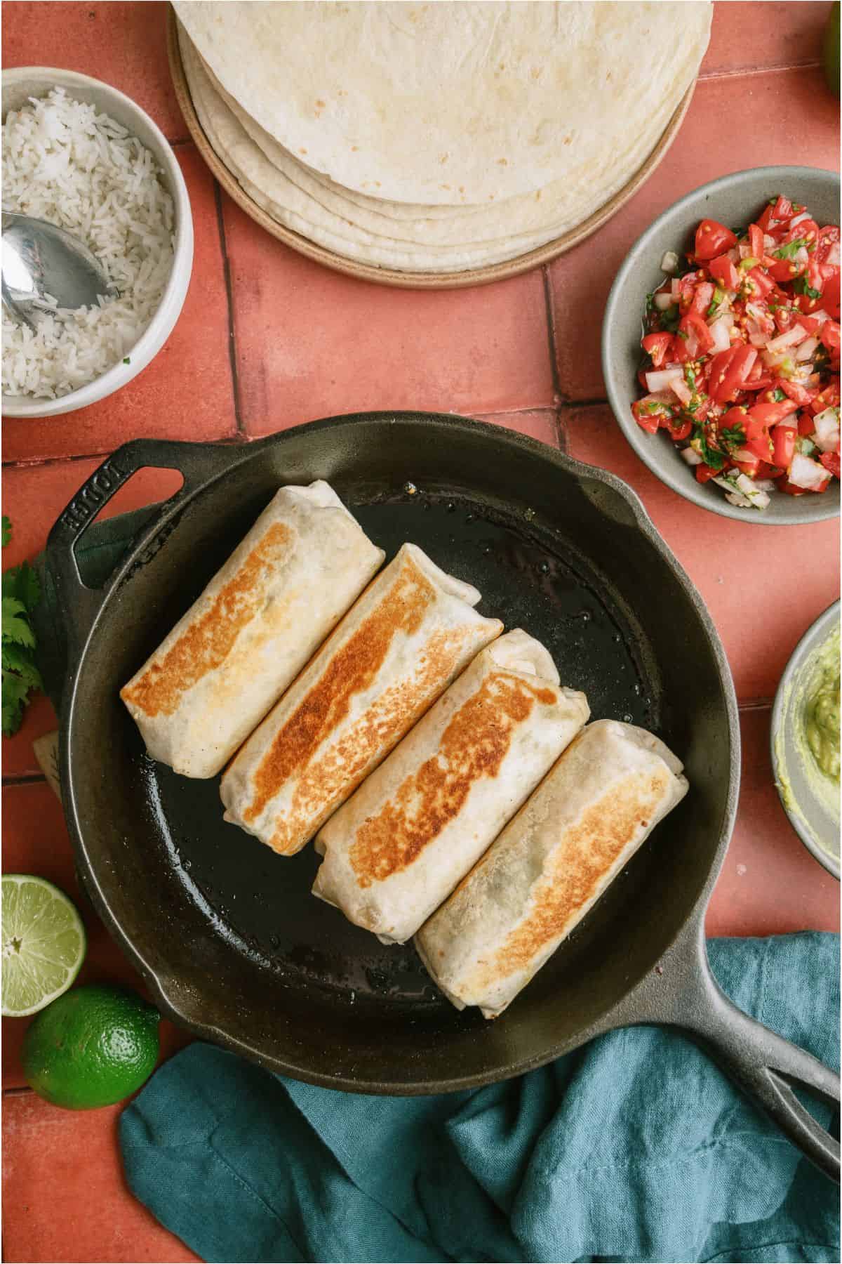 Crispy Steak Burritos browned in a skillet.