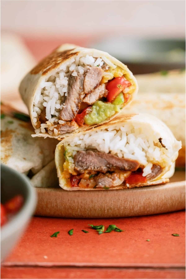 Close up of a Crispy Steak Burrito cut in half to show the ingredients on the inside.