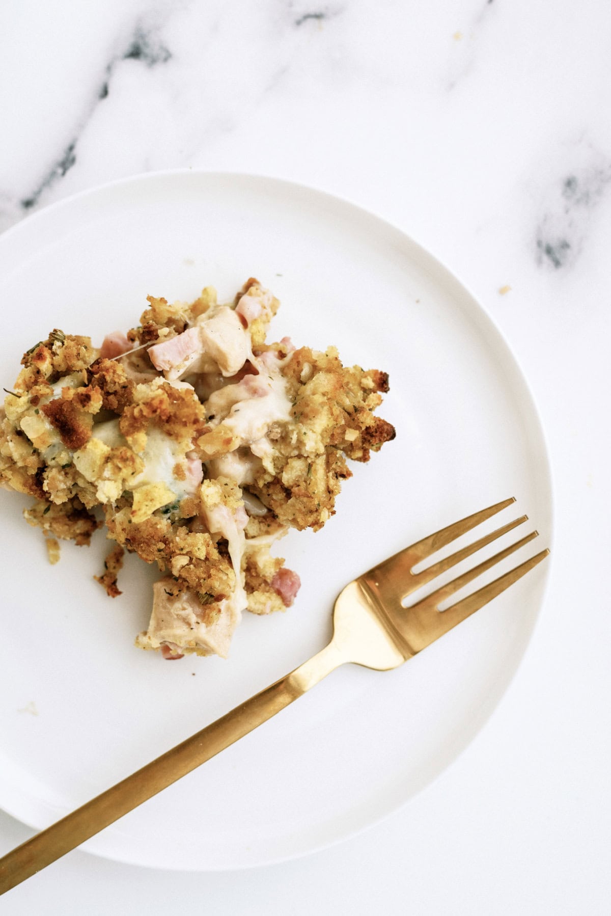 chicken cordon bleu casserole on a white plate with a gold fork