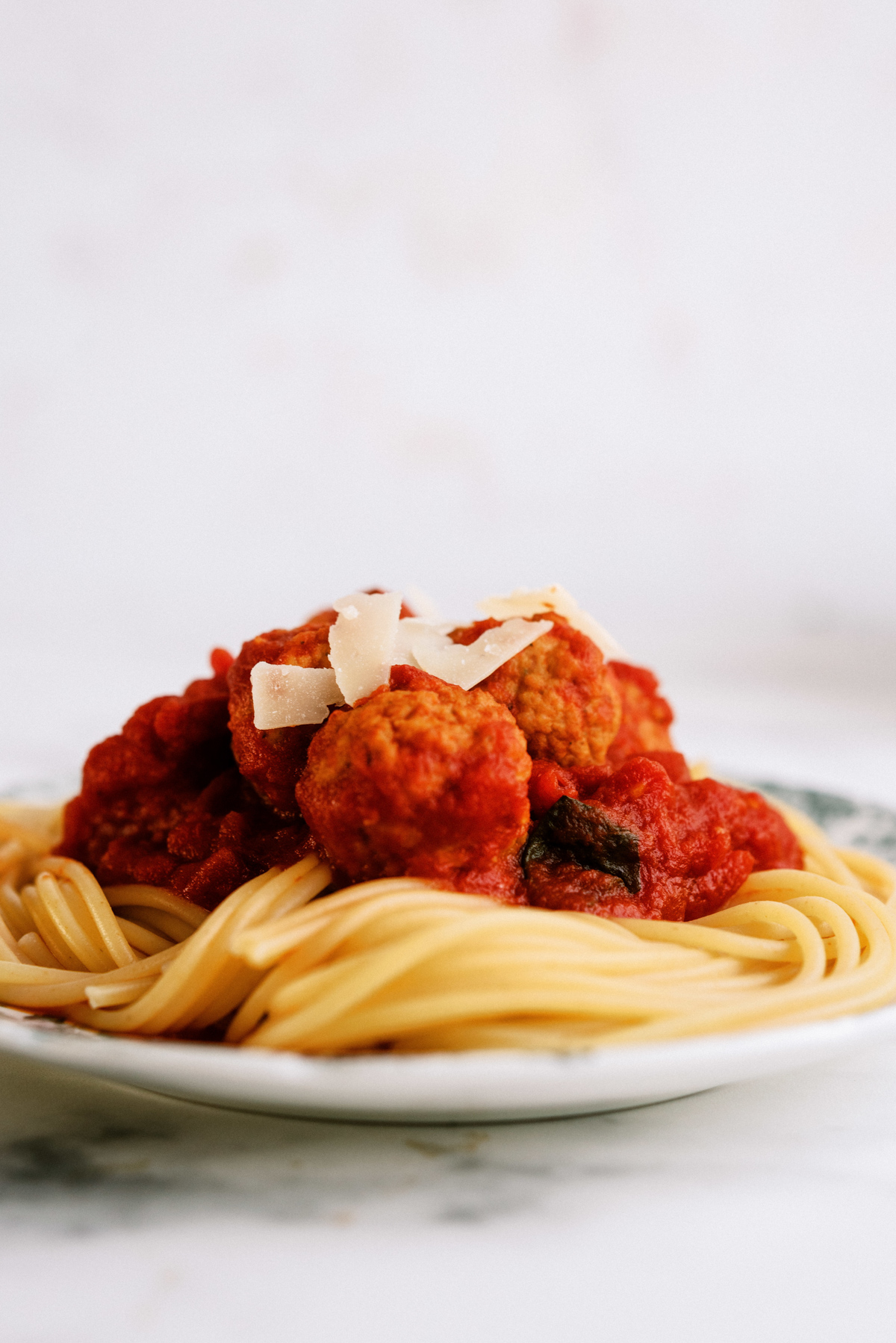 Instant Pot Italian Meatballs served over cooked spaghetti noodles with shaved parmesan cheese
