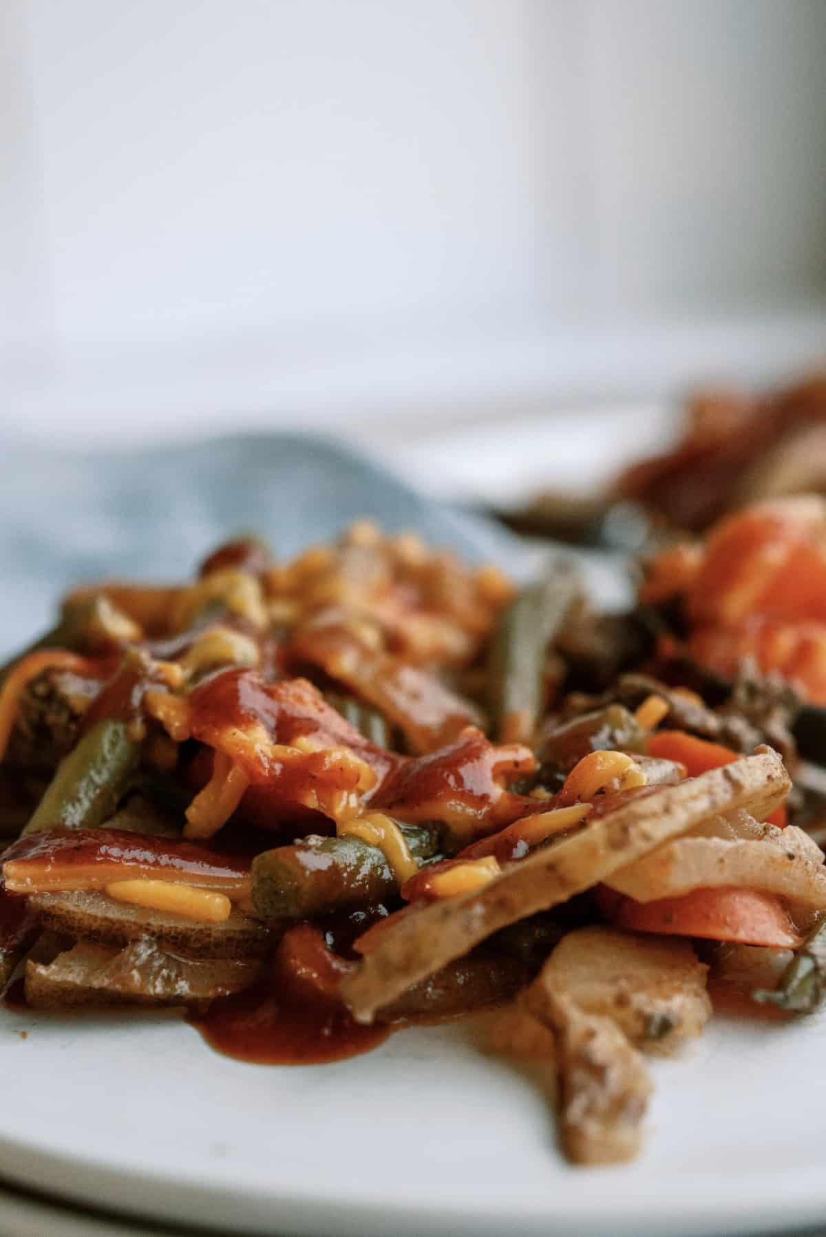 slow cooker ground beef hobo dinner topped with cheese and bbq sauce