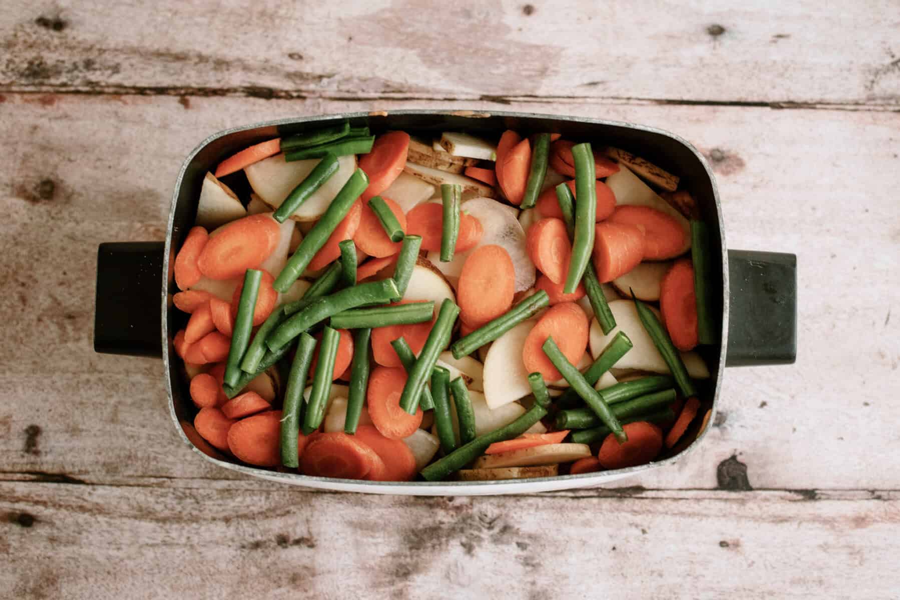 vegetables stacked in the bottom of the slow cooker