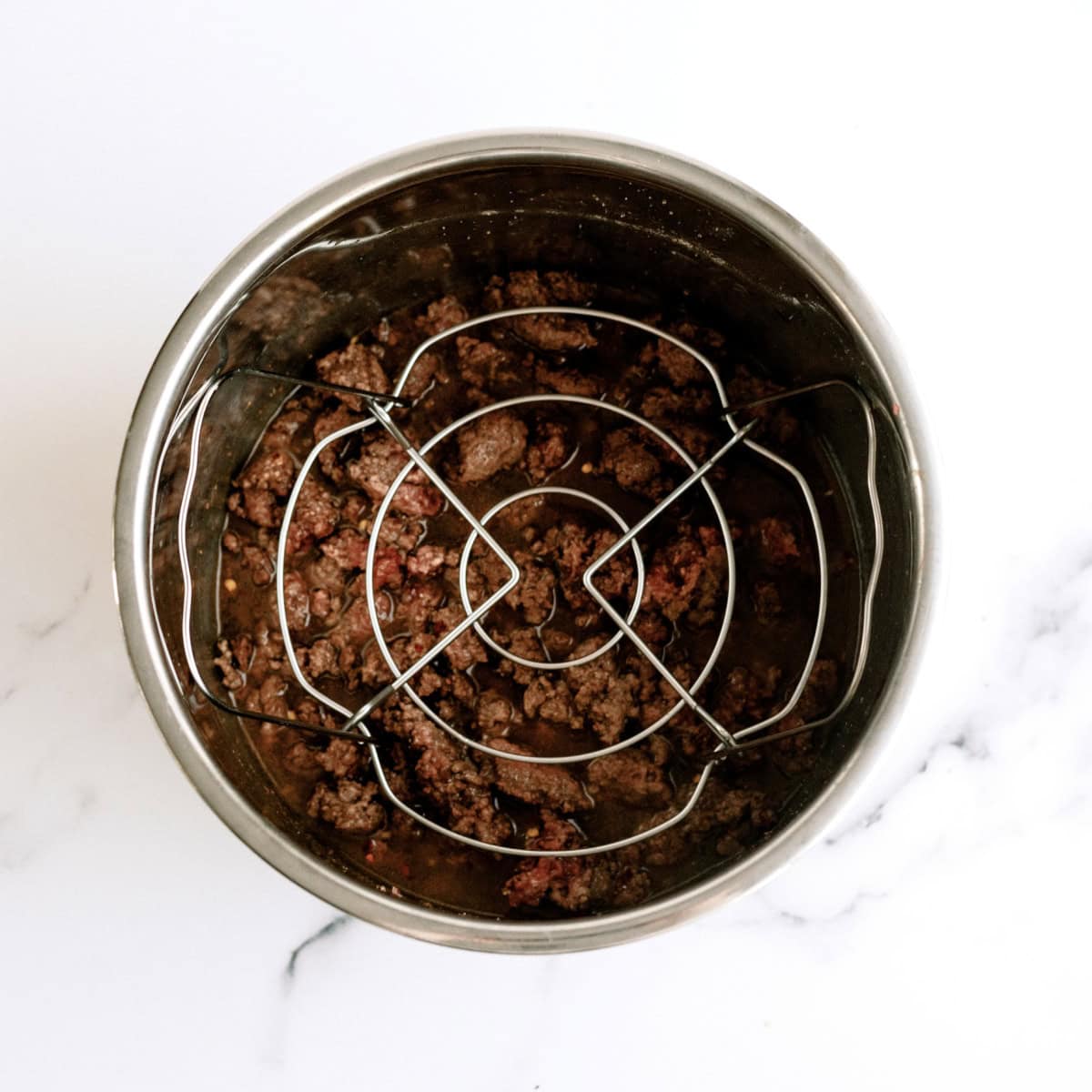 trivet placed on top of ground beef in the bottom of the instant pot