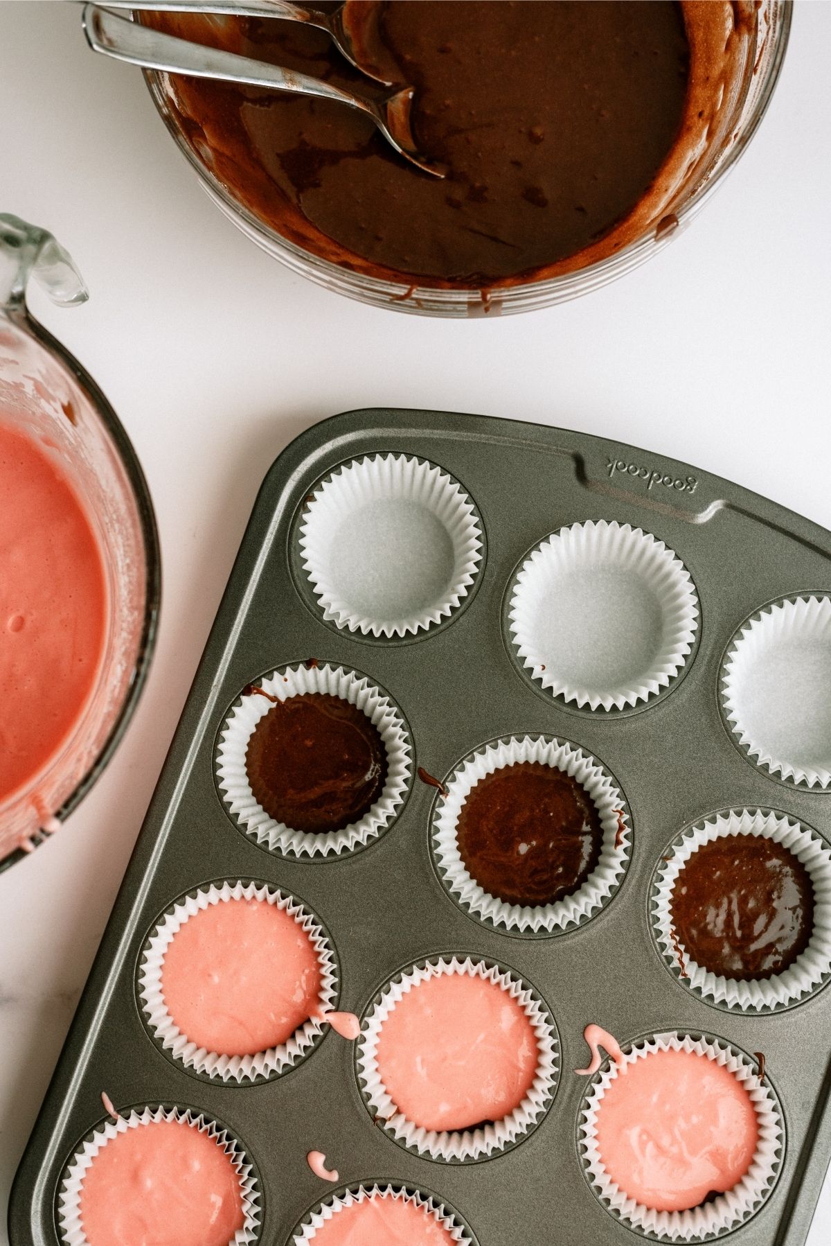 Muffin tin filled with brownie batter and strawberry cake for Neapolitan Cupcakes