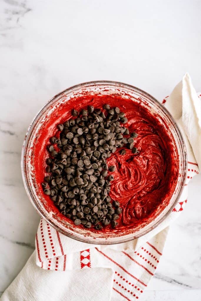 Add chocolate chips to red velvet brownie batter.