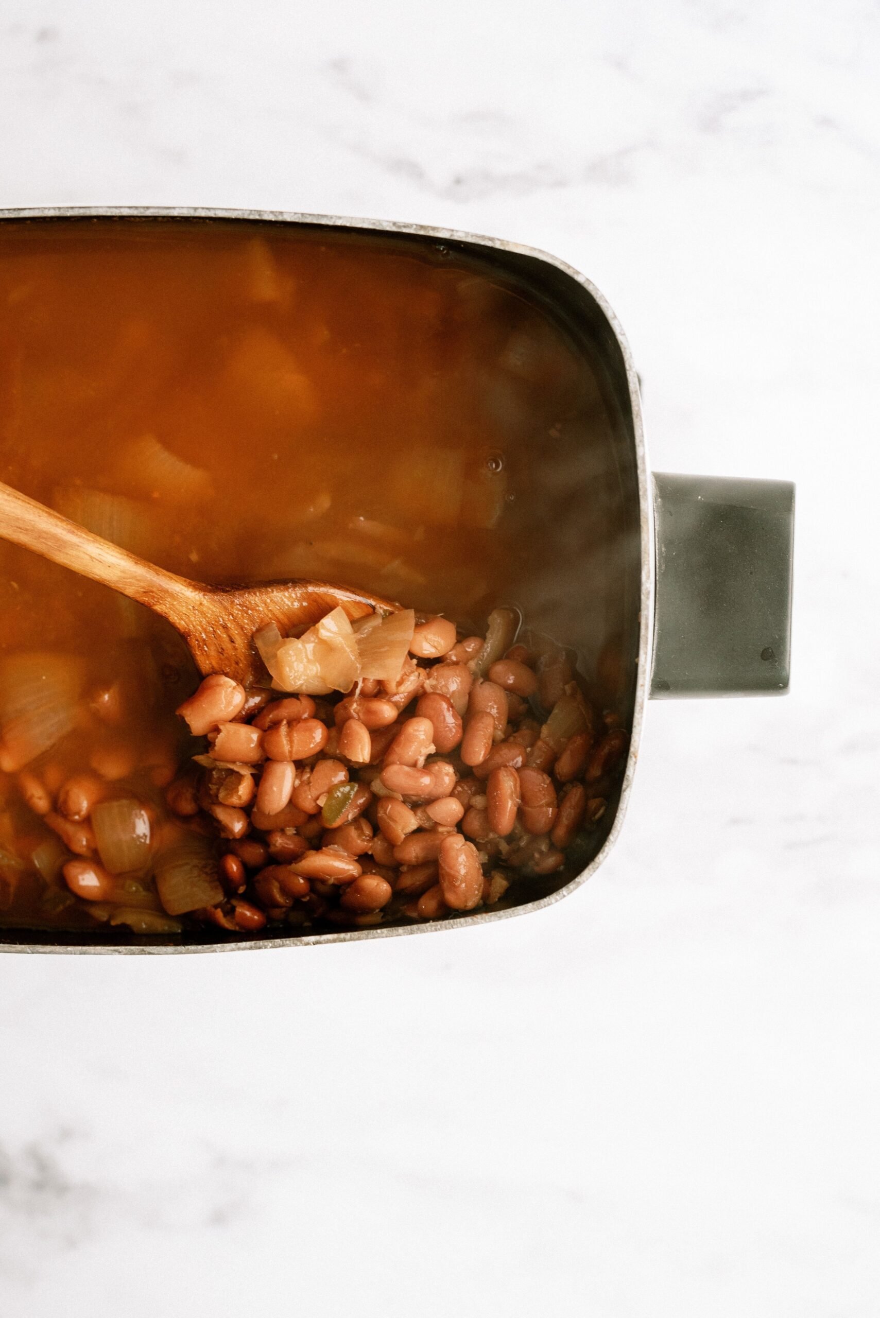 Slow Cooker Refried Beans in slow cooker with wooden spoon stirring