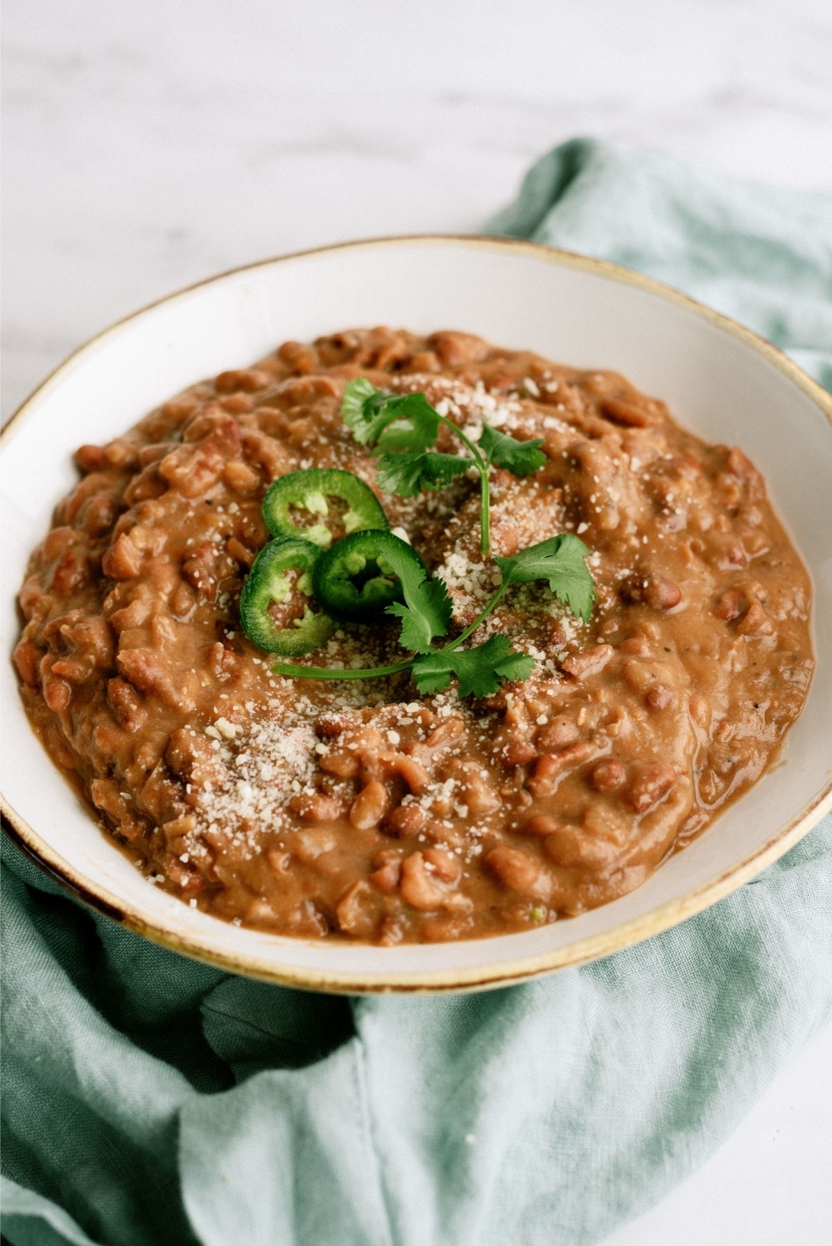 Slow Cooker Refried Beans in a bowl topped with peppers and cilantro