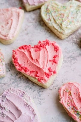 Sugar cookies shaped like hearts and frosted with pink. white and purple frosting.