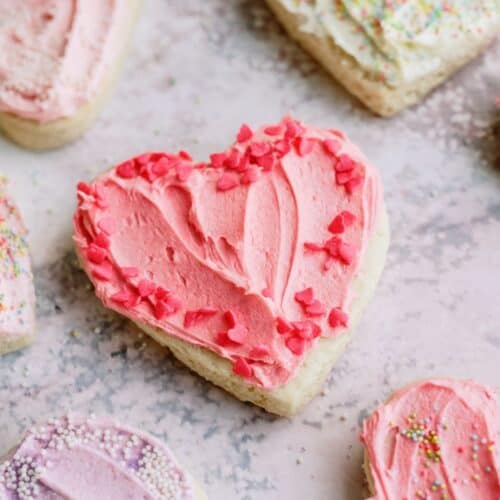 Sugar cookies shaped like hearts and frosted with pink. white and purple frosting.