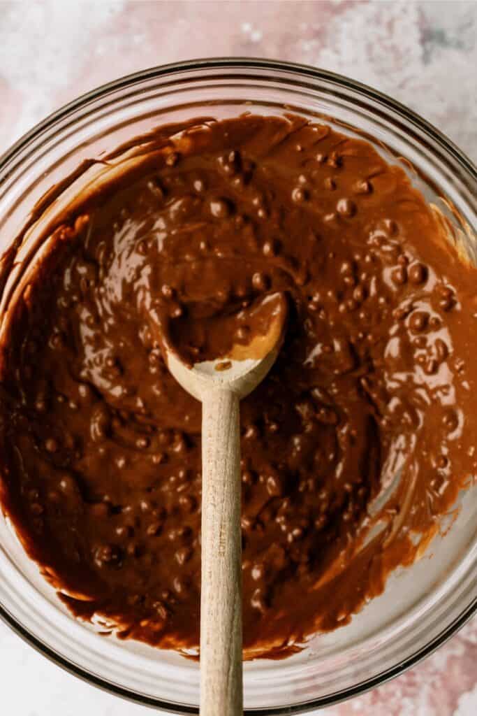 Melted Chocolate and Peanut Butter in a glass mixing bowl with a wooden spoon.