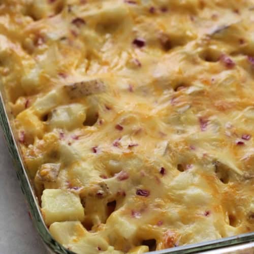 A glass baking dish filled with a baked casserole featuring melted cheese and visible chunks of potatoes.