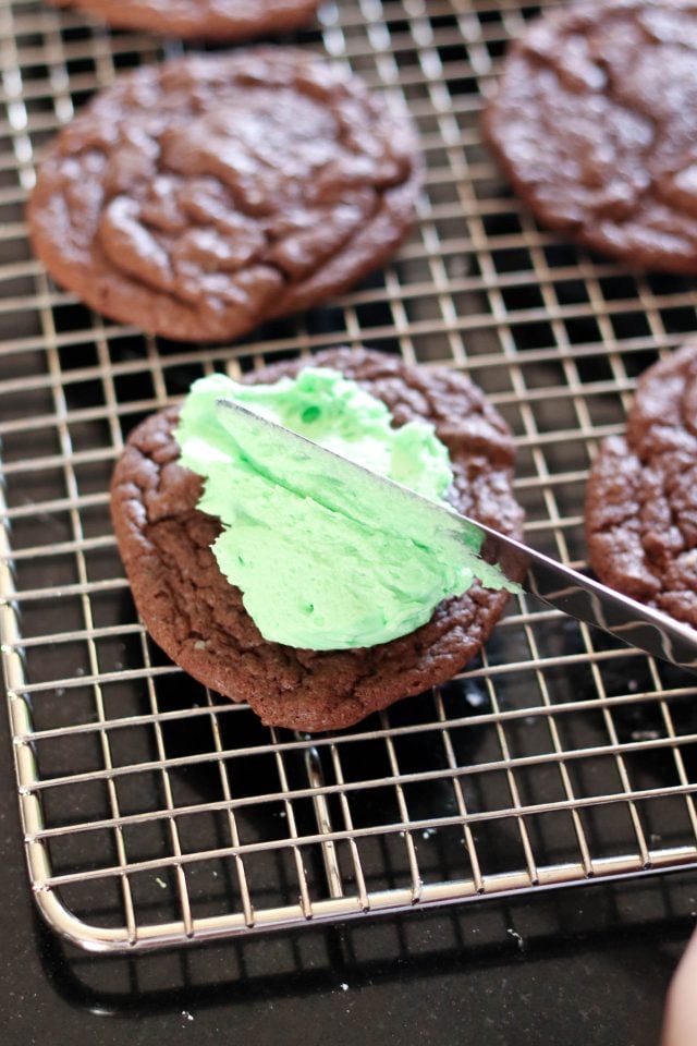Spreading mint frosting on chocolate cookies