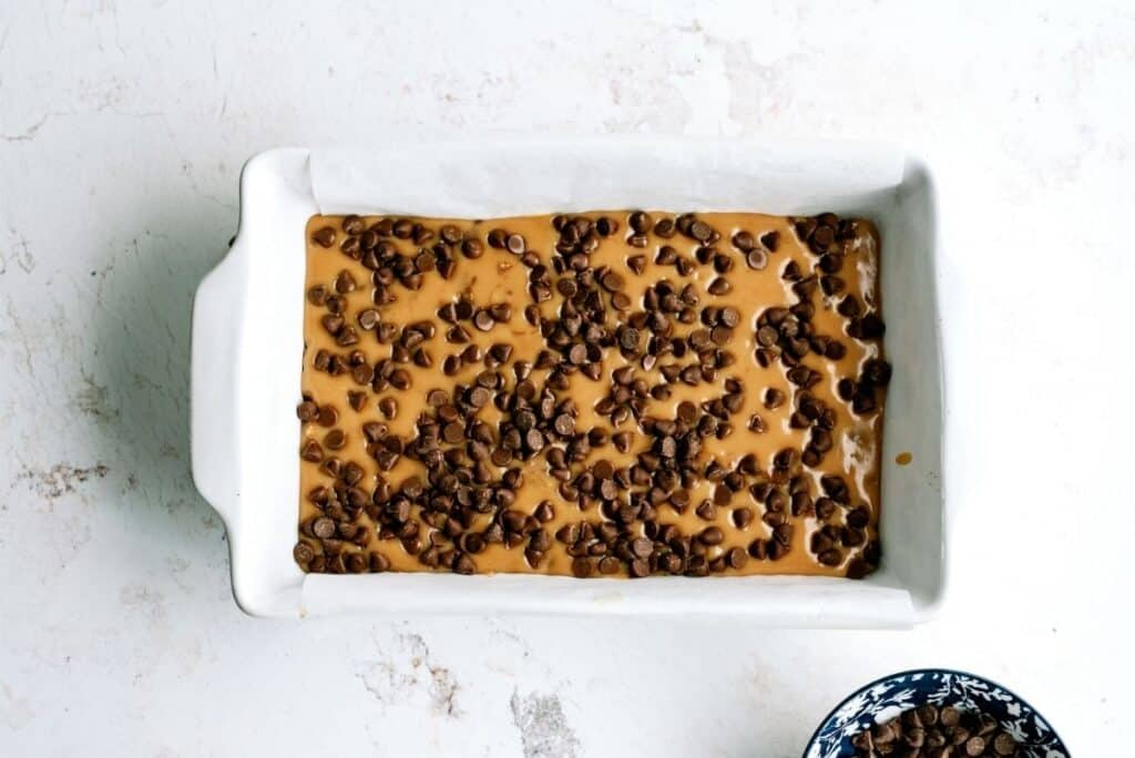 Chocolate chips sprinkled over melted caramel in baking dish.