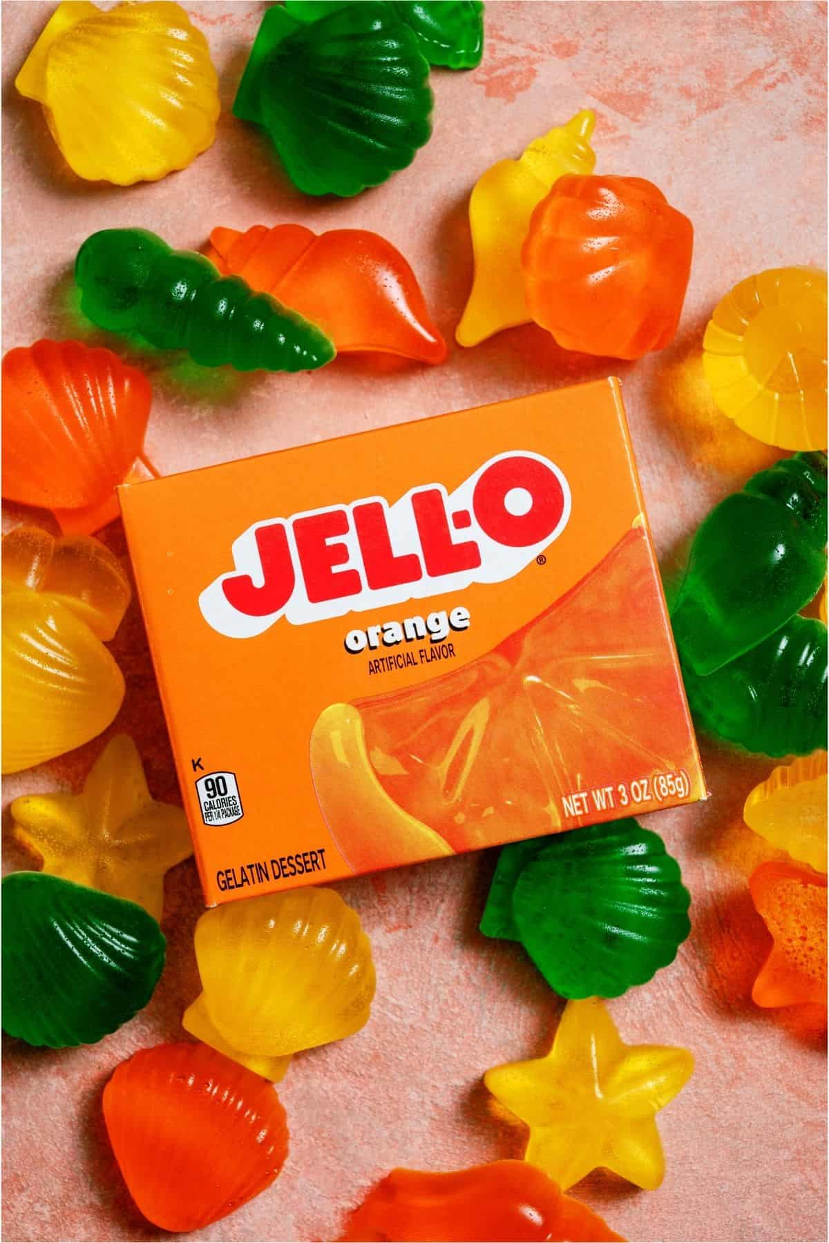 A box of Orange Jello surrounded by Homemade Jello Fruit Snacks.