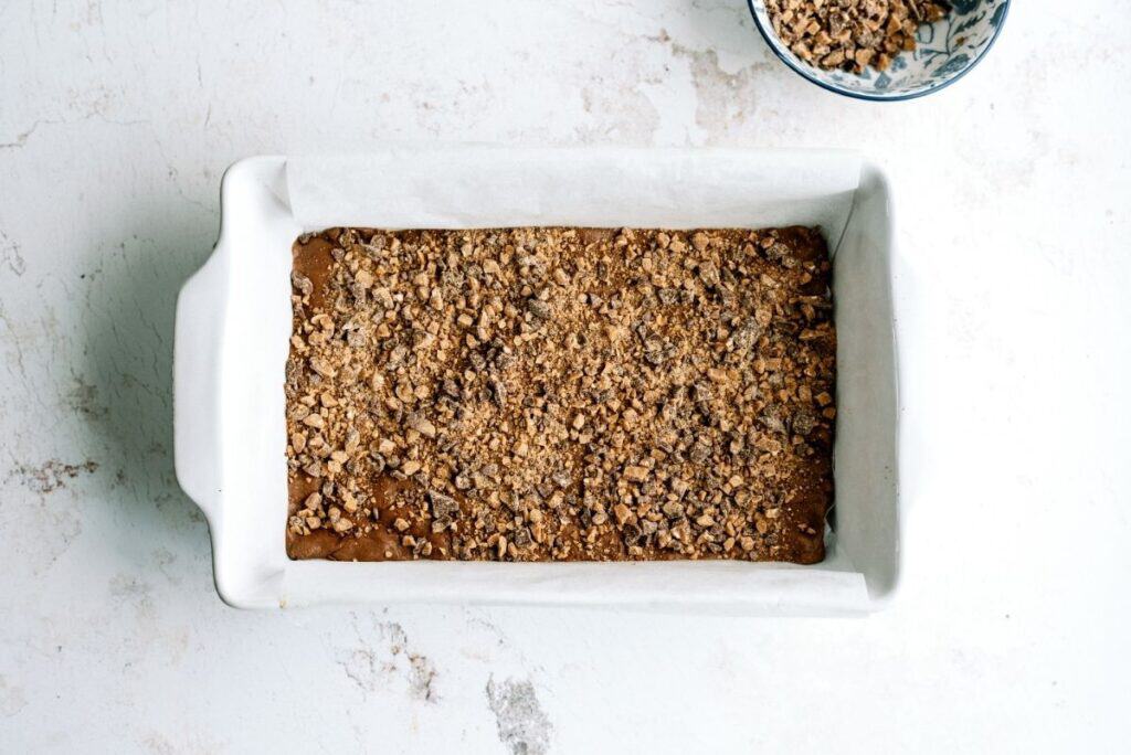 Heath toffee bits sprinkled over baked cake in baking dish.