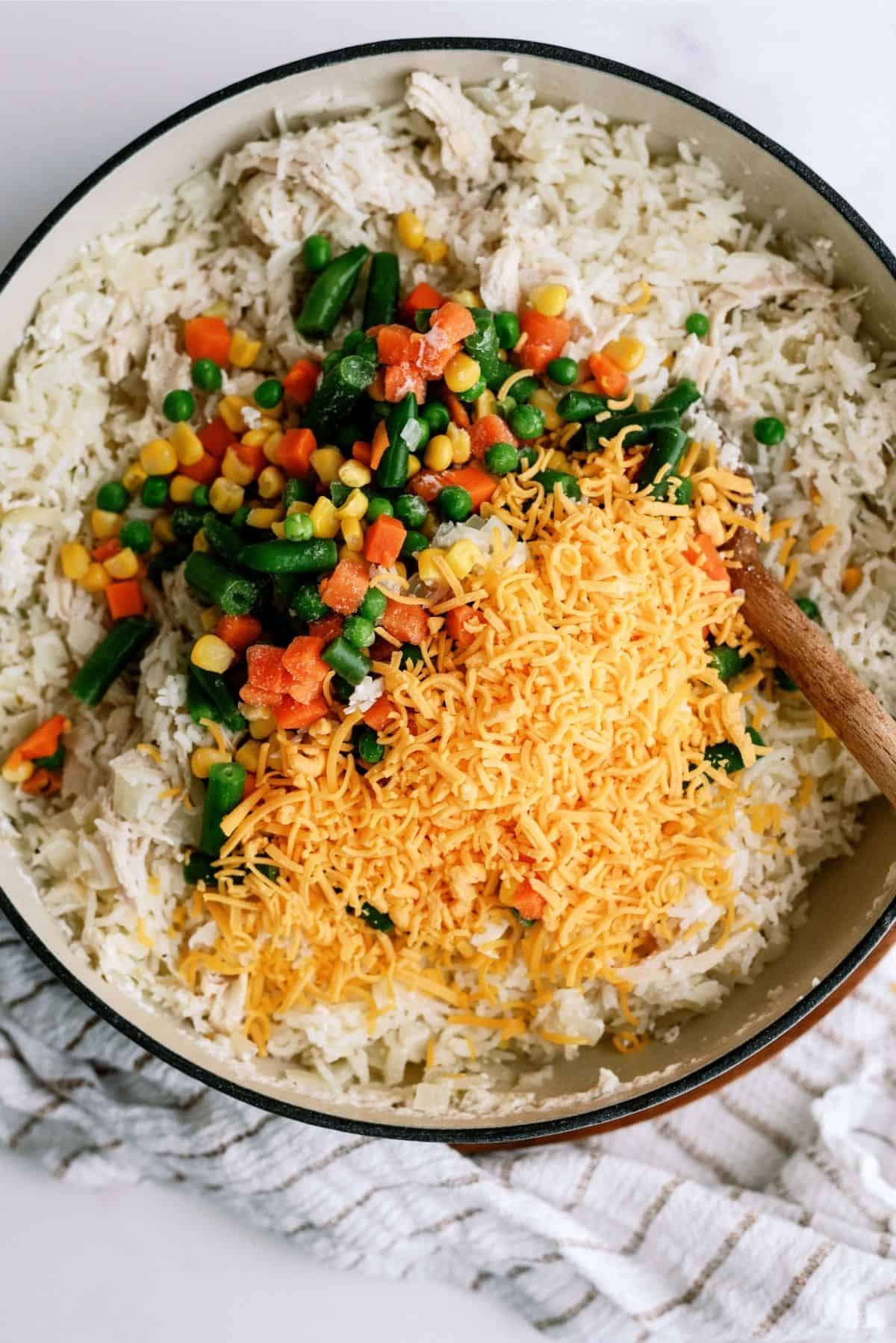 Add frozen vegetables and shredded cheese to pot for Creamy Chicken and Rice Casserole Skillet