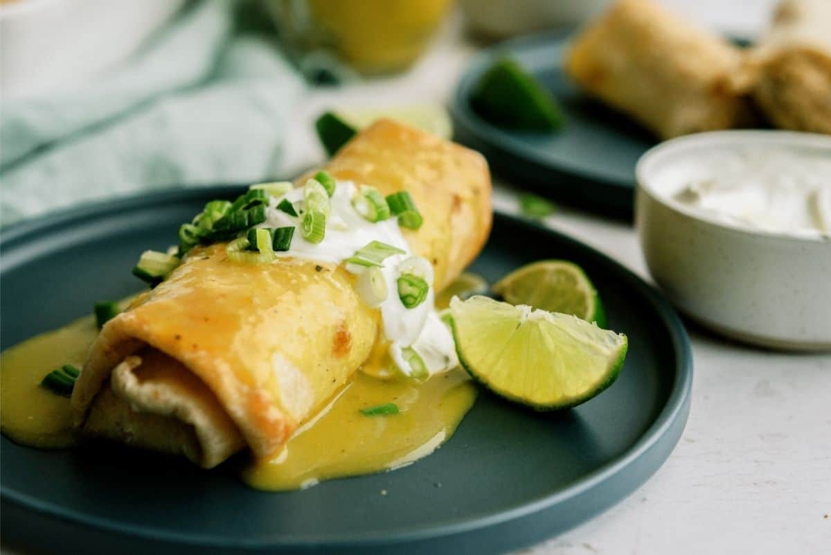 Baked Chicken Chimichanga on a black serving plate with lime wedges