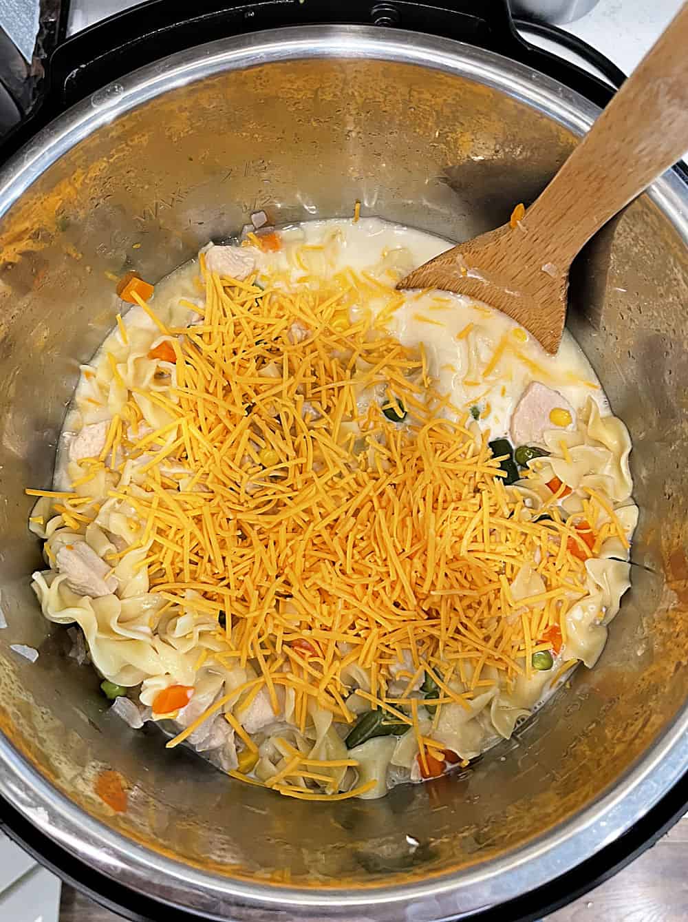 cheese mixed in with noodles and vegetables and chicken in pressure cooker