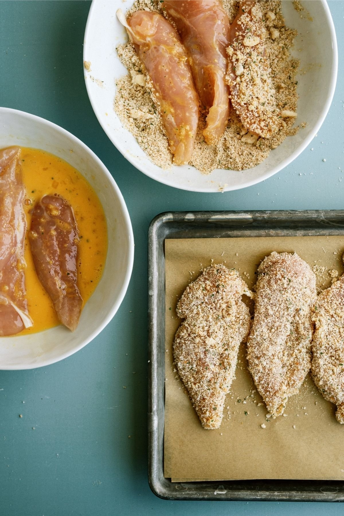 Chicken Tenders Dipped in Egg and Breadcrumbs placed on sheet pan