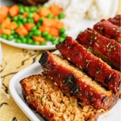 Easy Turkey Meatloaf on a serving platter sliced with a plate of vegetables in the background.