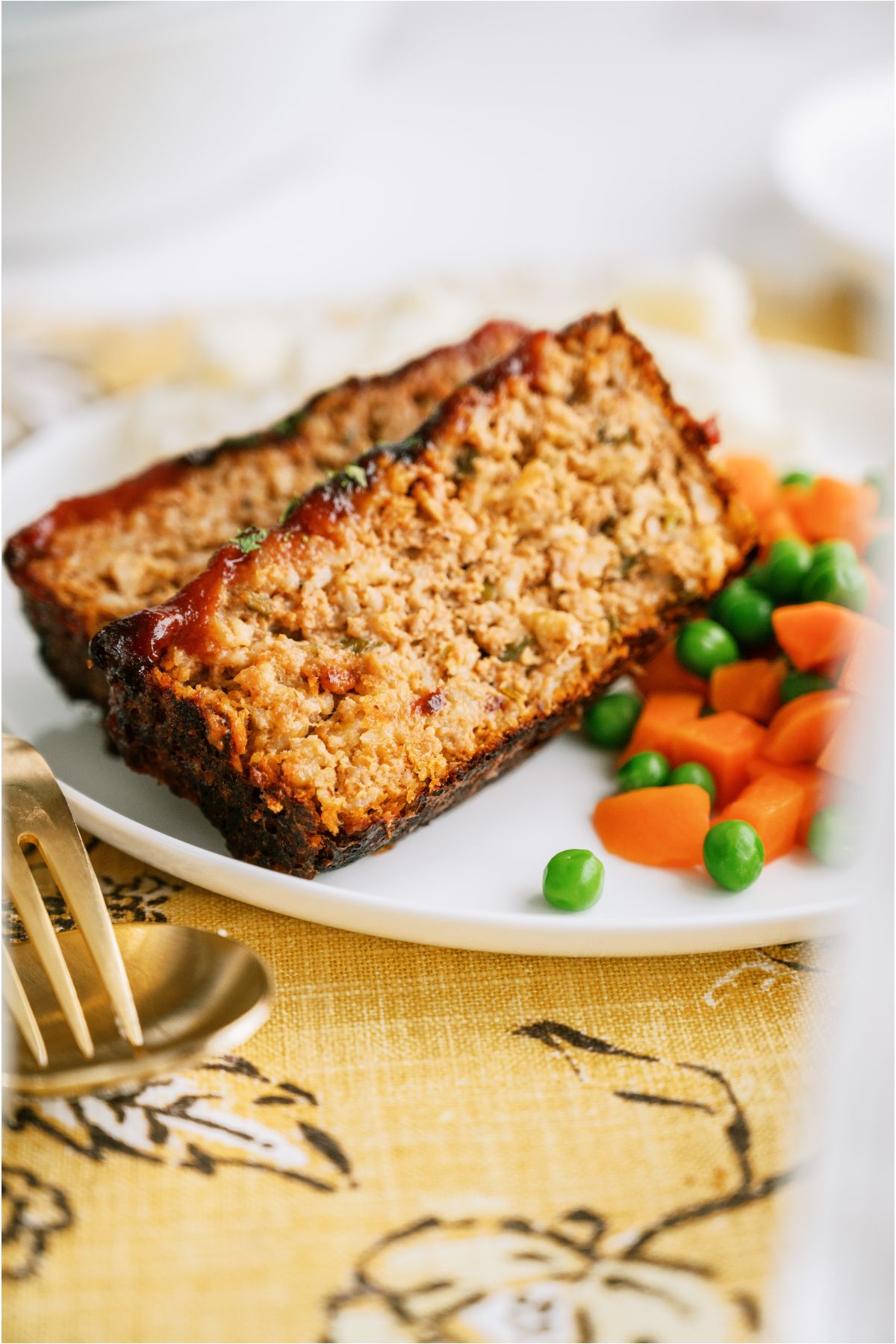 2 slices of Easy Turkey Meatloaf on a plate with mixed vegetables.