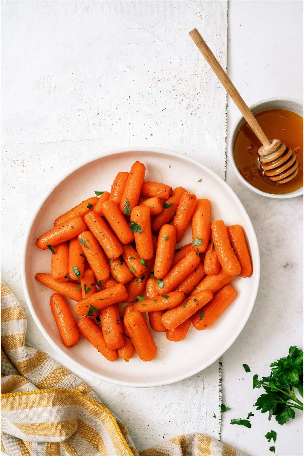 Top view of a plate of Honey Roasted Carrots with a honey pot next to it.