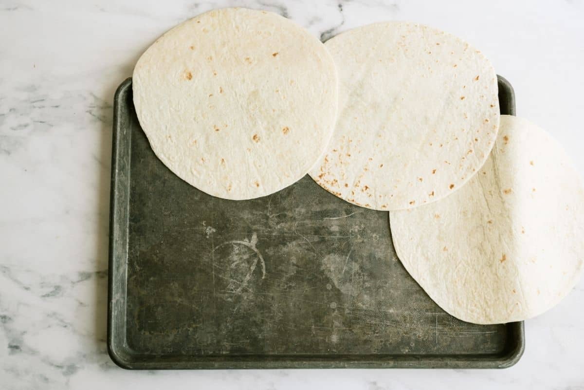 Line the edge of cookie sheet with tortillas for Sheet Pan Ground Beef Quesadillas Recipe