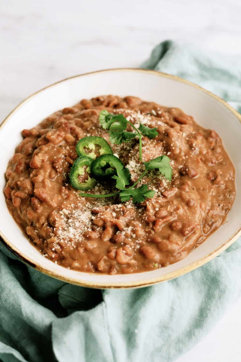 Refried beans with jalapeno, cilantro, and cotija cheese on top