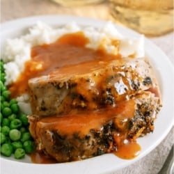 Slow Cooker Parmesan Slices of Honey Pork Roast on a plate with mashed potatoes and peas.