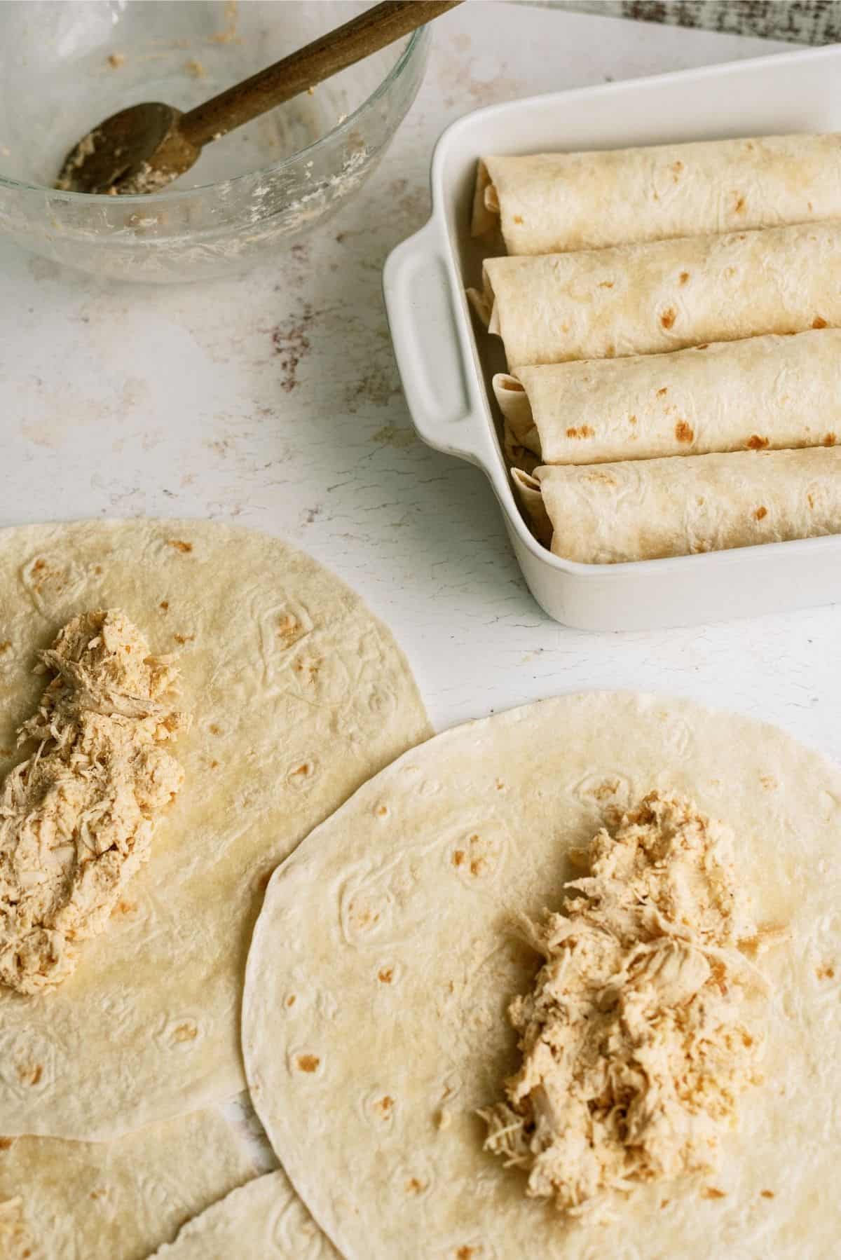 filled tortillas for Chimichangas, some rolled in dish others laying flat