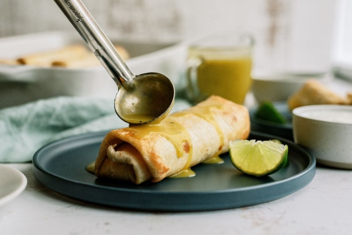 ladling green sauce over Baked Chicken Chimichangas