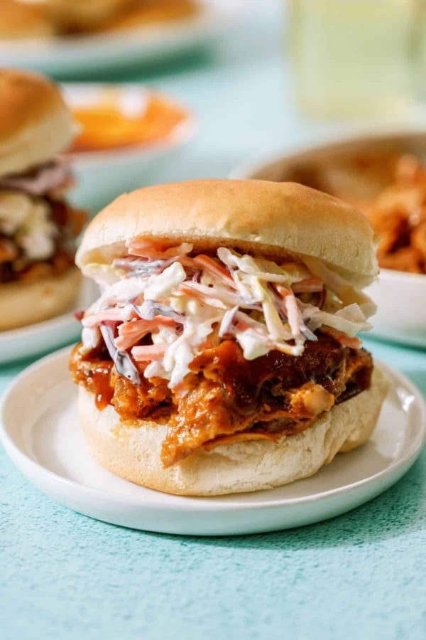 Bbq pork sandwich with coleslaw on a white plate.